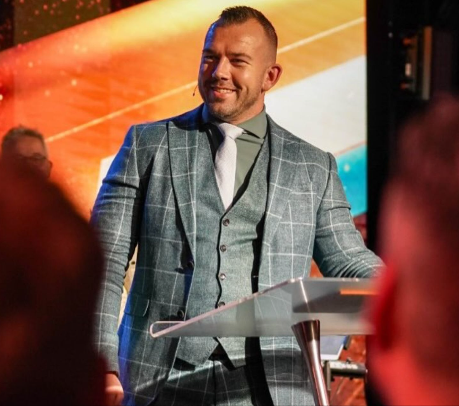 Tom de Wal spreekt achter een plexiglas preekstoel